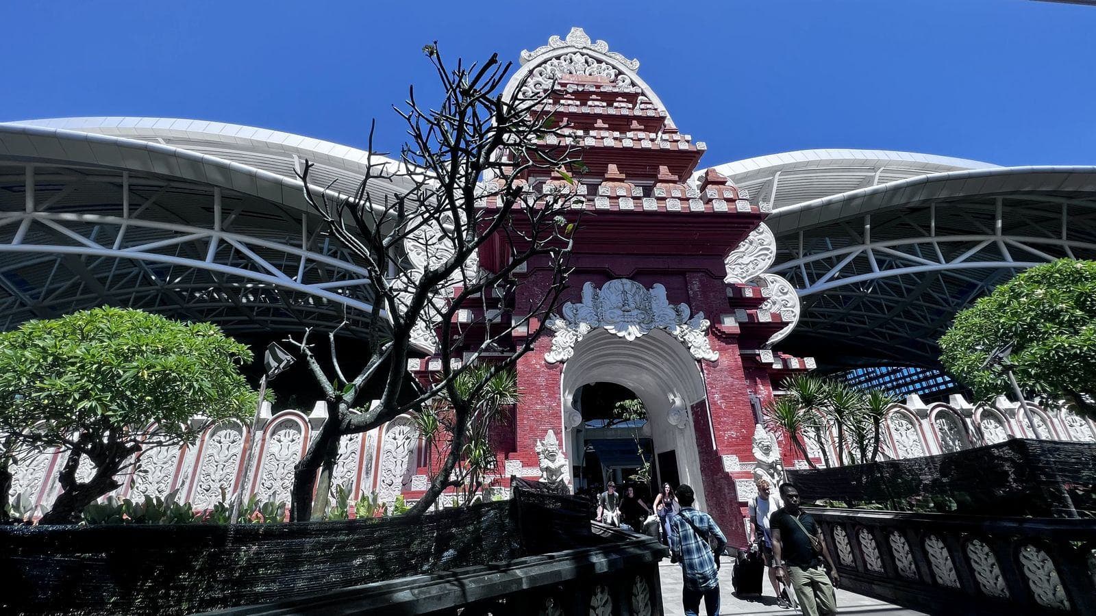Travelers walking out of the Balinese gate at Ngurah Rai International Airport in Bali